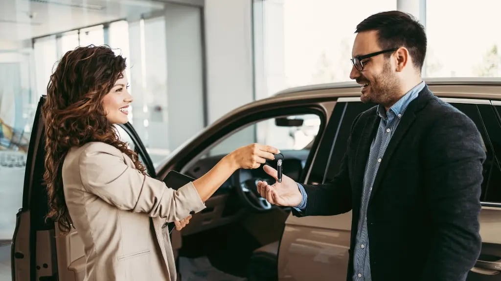 Autohändlerin überreicht Kunden den Schlüssel für das neue Fahrzeug und nutzt Absatzförderung am Point of Sale