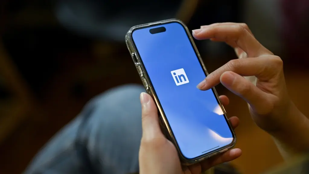 Smartphone mit LinkedIn Logo auf dem Bildschirm in einer weiblichen Hand.